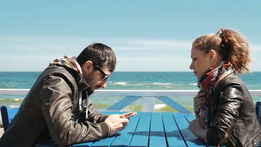 Девушка смотрит на парня, который сидит в телефоне.