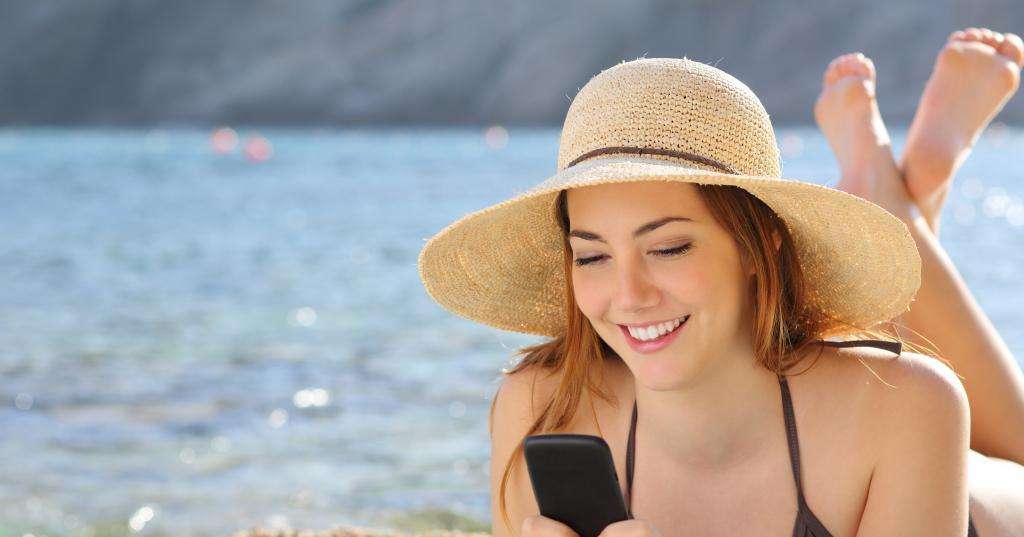 Девушка с телефоном на пляже.
